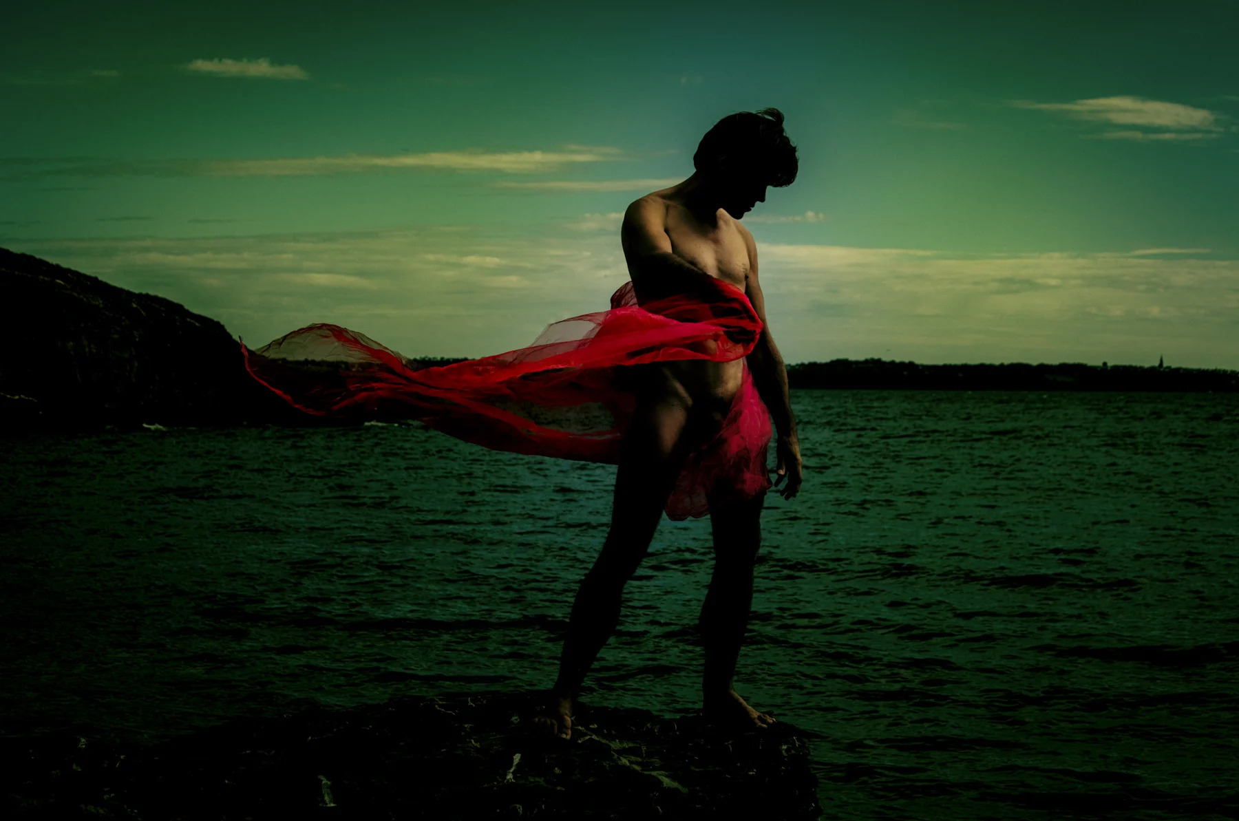Figure with red fabric by the water